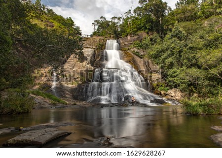 Diyaluma, Haputale, Sri Lanka. 2019 Nov 22:  Young tourist men in the Sunny day in the Tropical waterfall falls from the mountain cliff to the jungle, serene landscape of Diyaluma falls.