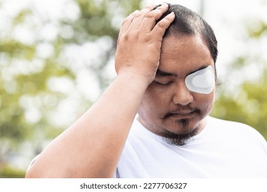 Dizzy Asian middle-aged man patient with eye patch, eye sight impair with headache - Powered by Shutterstock