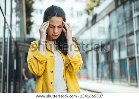 Dizzy woman complaining in the street. Young woman standing suffering for headache at street. Woman standing with eyes closed and head in hands on street