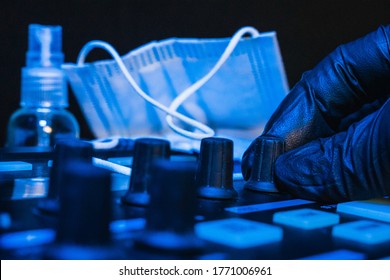 A DJ Changing The Tune On His Soundboard With Black Gloves And Medical Mask On The Background