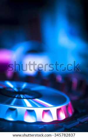 DJ console cd mp4 deejay mixing desk Ibiza house techno dance music wedding reception party in nightclub with colored lighting effect disco lights.