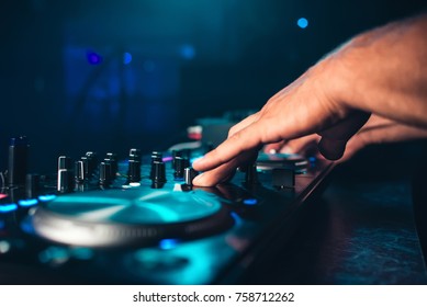 DJ controls and mix music on music mixer in nightclub
