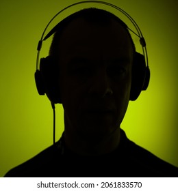 Dj deejay electronic wearing music headphones with coloured lights plain studio background.