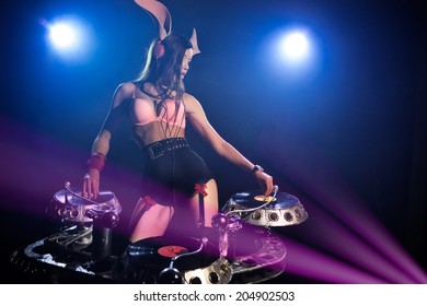 DJ girl in sexy pink bunny suit playing on vinyl