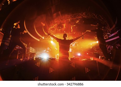 DJ hands up with crowd of people in night club party under red light - Powered by Shutterstock