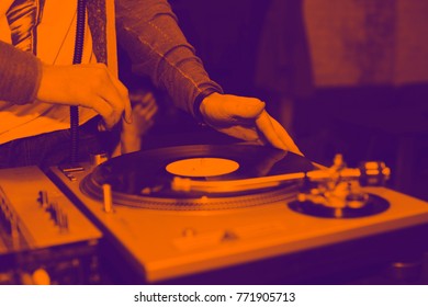 Dj mix tracks at party on vinyl record player. The Duotone effect - orange and purple