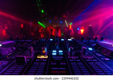 DJ Mixer Controller Board For Professional Mixing Of Electronic Music In A Nightclub At A Party With Dancing People