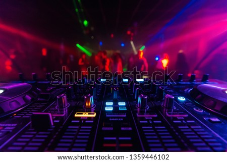 DJ mixer controller Board for professional mixing of electronic music in a nightclub at a party with dancing people