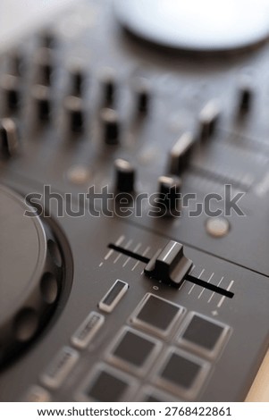 Dj mixer fader and knobs on black controller surface.