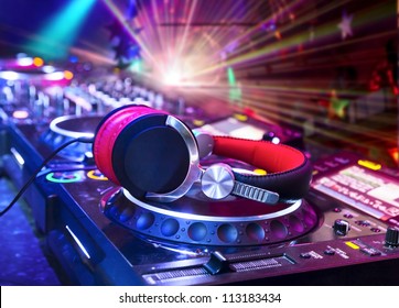 Dj mixer with headphones at nightclub.  In the background laser light show