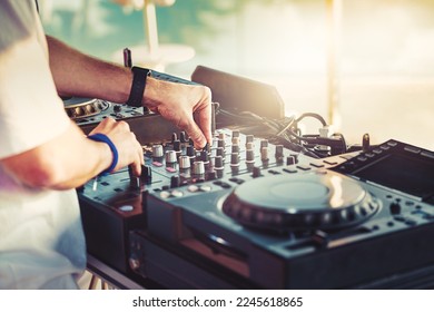 DJ is mixing music with deejay controller at outdoor summer pool or beach party - nightlife people lifestyle concept - Shutterstock ID 2245618865