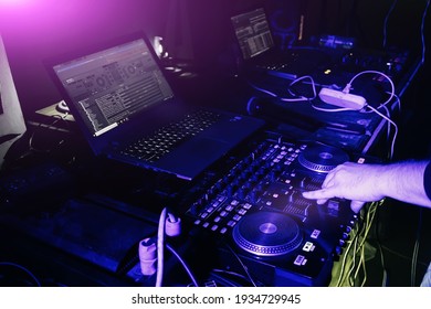 DJ mixing music on turntable console at in the night club.