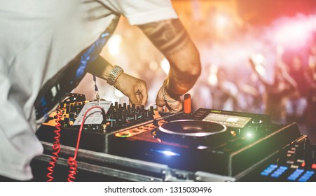 Dj mixing outdoor at beach party festival with crowd of people in background - Summer nightlife view of disco club outside - Soft focus on right hand - Fun ,youth,entertainment and fest concept