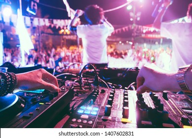 Dj mixing outdoor at beach party festival outdoor with crowd of people in background - Soft focus on left hand - Fun, summer, youth, nightlife, music, nightclubs and entertainment concept - Shutterstock ID 1407602831