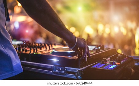 Dj mixing outdoor at beach party festival with crowd of people in background - Summer nightlife view of disco club outside - Soft focus on hand - Fun ,youth,entertainment and fest concept - Shutterstock ID 670249444