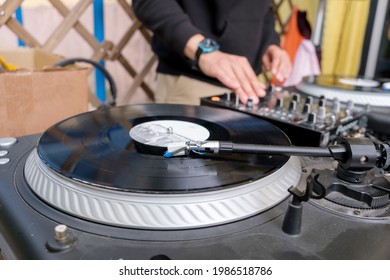 DJ Playing Mixing Music On Vinyl Turntable At Party. Unrecognizable Young White DJ At The Music Desk During A DJ Set On The Terrace Of A Trendy Youth Bar.