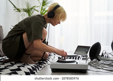 DJ playing music. Woman sitting with midi controller and disc jockey mix music at home. New digital technology for mixing audio tracks. Sound mixer with turntables