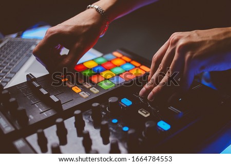 Dj plays beats on drum machine.Hip hop disc jockey playing on concert stage with professional midi controller device. Beat machine device for electronic music composer.  vintage photo processing