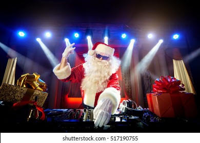 DJ Santa Claus mixing up some Christmas event.  Disco light around fun, colorful atmosphere. Musical New Year.