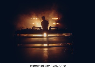 DJ set on a stage, silhouette in a warm backlight with two turntables