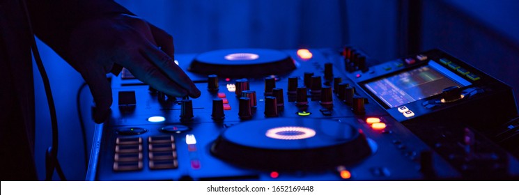 DJ Spinning, Mixing, and Scratching in a Night Club. DJ playing music at mixer . Closeup. Party.