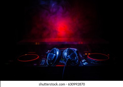 DJ спиннинг, смешивание и царапина в ночном клубе, руки dj настроить различные элементы управления треком на палубе dj, стробоскопы и туман, селективный фокус, близкий
