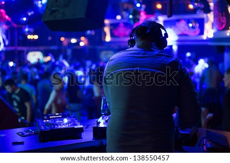 DJ turns the records at the club under the blue light