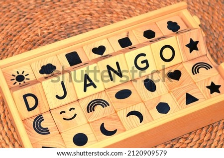 DJANGO word text from wooden cube block letters on braided rattan mats background. Django is a Romany term meaning 