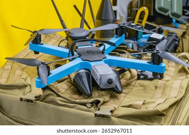 DJI Mavic Pro drone on green fabric surface amidst military equipment, indoor environment, foldable arms and propellers black silver, perspective from above