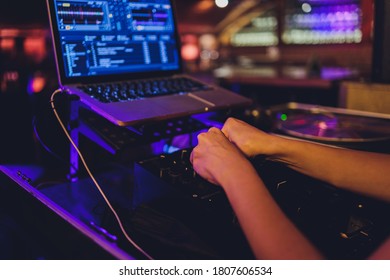 DJ's hand over the laptop and mixing console controlling the sound settings. - Shutterstock ID 1807606534