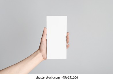 DL Flyer Mock-Up - Male hands holding a blank flyer on a gray background. - Shutterstock ID 456651106