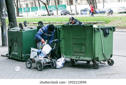 Dnepropetrovsk, Ukraine - 04.06.2021: Dirty Tramps Search For Food And Used PET Bottles In A Trash Bin On The Street. Homeless Men Have No Money Or Housing.