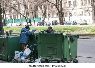 Dnepropetrovsk, Ukraine - 04.06.2021: Dirty Tramps Search For Food And Used PET Bottles In A Trash Bin On The Street. Homeless Men Have No Money Or Housing.