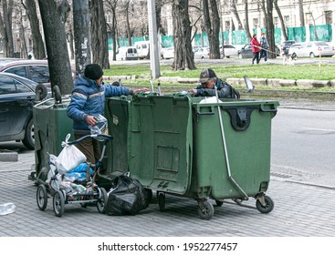 Dnepropetrovsk, Ukraine - 04.06.2021: Dirty Tramps Search For Food And Used PET Bottles In A Trash Bin On The Street. Homeless Men Have No Money Or Housing.