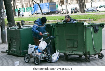 Dnepropetrovsk, Ukraine - 04.06.2021: Dirty Tramps Search For Food And Used PET Bottles In A Trash Bin On The Street. Homeless Men Have No Money Or Housing.