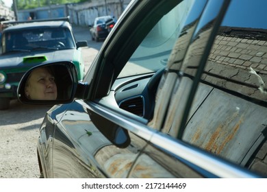 Dnepropetrovsk, Ukraine - 06.08.2022: AUDI Q3 In Black. Subcompact Luxury Crossover Audi Q3. View Of The Side Mirror Reflecting The Face Of The Female Driver.