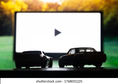 DNIPRO, UKRAINE - 06.18.2020: Drive-in theater or drive in cinema, open air movie. Two cars on the background of a large movie screen, outdoors.