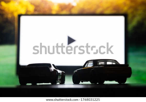 DNIPRO, UKRAINE - 06.18.2020: Drive-in theater\
or drive in cinema, open air movie. Two cars on the background of a\
large movie screen,\
outdoors.