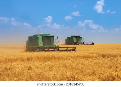 Dnipro. Ukraine 10 July 2021. Two green harvesters harvest golden wheat. Harvester machine to harvest wheat field working. Combine harvester agriculture machine harvesting golden ripe wheat field. 