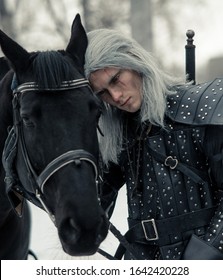 Dnipro, Ukraine - February 06, 2020: Portrait Of Cosplayer In Image Of A Character Geralt Of Rivia From The Game Or Film The Witcher Next To A Horse In Forest.