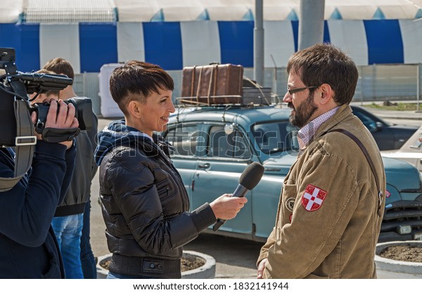 Dnipro,\
Ukraine - October 30, 2013: Woman correspondent interviews driver\
retro car of participant in rally of vintage\
cars