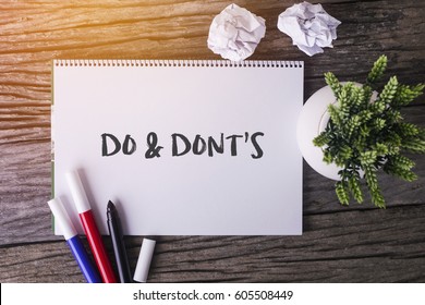 Do And Dont's word with Notepad and green plant on wooden background