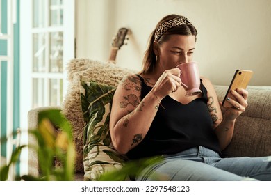 Do downtime your way. a young woman having coffee and using a smartphone on the sofa at home. - Powered by Shutterstock