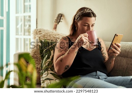 Do downtime your way. a young woman having coffee and using a smartphone on the sofa at home.