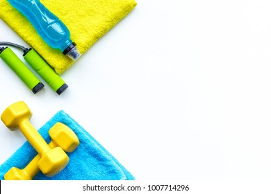 Do Fintess In Gym. Dumbbells, Jump Rope, Mat, Water On White Background Top View Space For Text Pattern