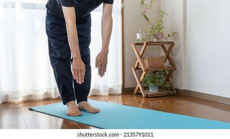 Do A Forward Bending Exercise.A Man Stretching In The Room. The Body Is Stiff.