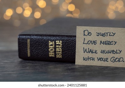Do justly, love mercy, walk humbly with your God, handwritten biblical quote, Micah 6:8 and holy bible with bokeh background. Christian concept.