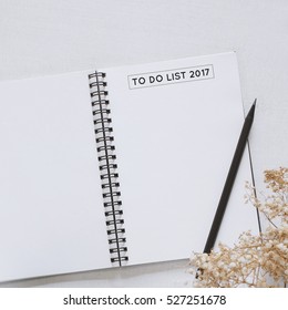 To do list 2017 on notebook with flower on white background, top view with minimal style