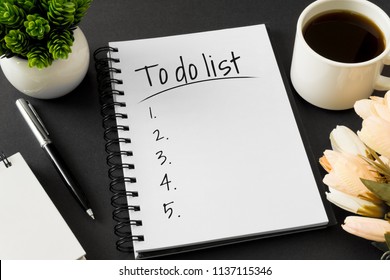 To do list. Notebook and coffee cup on black background.