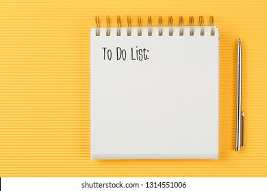 to do list notebook on corrugated yellow background with pen top view, spiral notepad with blank sheet, flat lay